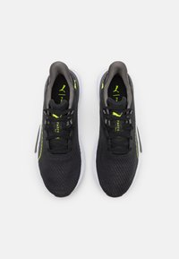 Scarpe sportive in rete nera con accentuazioni grigie e dettagli di colore giallo neon; presentano una suola bianca e un sistema di allacciatura standard.