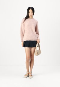 Fluffy pink sweater, black pleated skirt, beige bag, and light shoes with buckle accents. Simple design, soft texture, and neutral color palette.