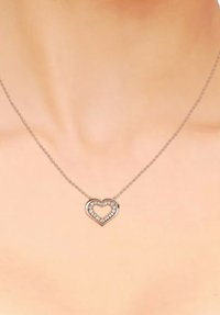 Collana in oro rosa con un pendente a forma di cuore caratterizzato da un contorno di pietre trasparenti e un centro vuoto, appoggiato su una delicata catena.