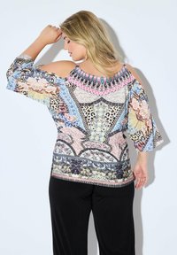Koude schouder top in kleurrijke bloemen- en geometrische patronen met korte mouwen. Lichte stof met een losse pasvorm, voorzien van een decoratieve halslijn.