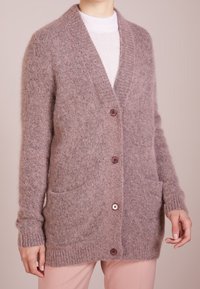 Luddig, långärmad cardigan i ljus mauve, med V-ringning, fyra knappar, ribbade ärmslut och två framfickor.