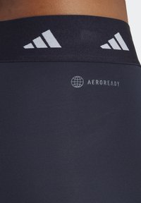 Leggings sportivi blu navy con una cintura testurizzata caratterizzata da tre strisce bianche e un logo Aeroready in grigio. Materiale morbido e elastico.