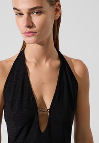 Mustast säärtega kaelaga bodi, millel on sügav V-kaelus, läikiv tekstuur ja hõbedane logo rinnal.