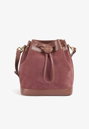 Taštička tvaru koša z bordovej semišovej kože s hnedými koženými doplnkami, horné sťahovanie na šnúru a nastaviteľný popruh. Zlaté logo vpredu.