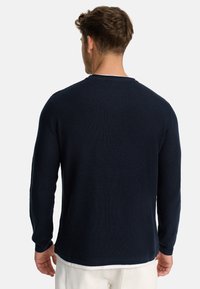 Navyblå tekstureret langærmet skjorte med rund halsudskæring og ribbet kant. Stofmet viser et vaffelmønster, hvilket giver et afslappet udseende.