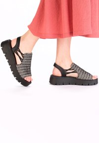 Sandales à plateforme noires avec un dessus tissé dans un motif monochrome. Comprend une ouverture à l'avant, des brides autour de la cheville et une semelle en caoutchouc texturé.