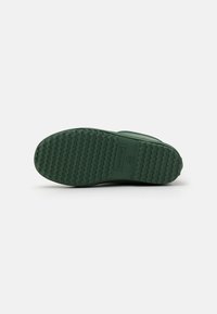 Suola di gomma verde con un motivo zigrinato a zigzag per una migliore aderenza, con la scritta "HUNTER" impressa sul lato. Design liscio e curvo.