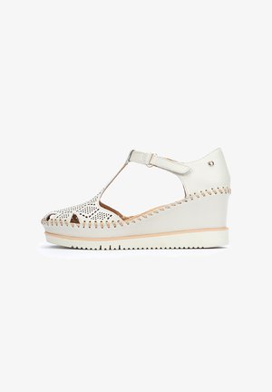 Sandalias de cuña blancas con parte superior de cuero perforado, correa ajustable y costuras en contraste. Cuenta con una suela texturizada para un mejor agarre.