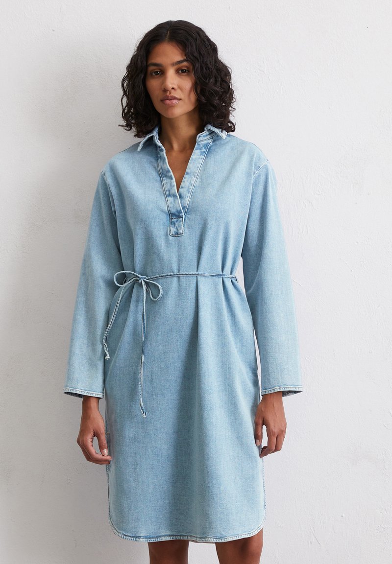Robe en denim bleu clair avec un col, des manches longues et une taille cintrée. Elle présente une patte de boutonnage avant et des coutures contrastantes au niveau de l'ourlet.