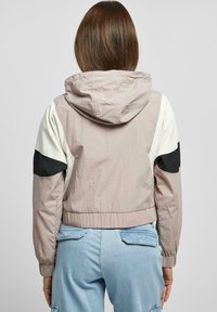 Lätt, kort jacka med huva, i nyanser av beige, off-white och svart. Strukturerad tyg med elastiska ärmslut och nederkant.
