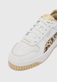 Baskets en cuir blanc avec une semelle en caoutchouc beige clair, ornées d'un accent imprimé léopard sur le côté et de lacets plats blancs.