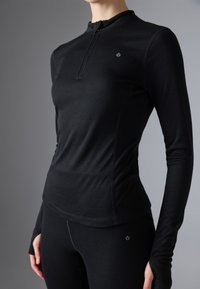 Czarna, długi rękaw, sportowa koszulka z zamkiem przy szyi, dopasowany krój, gładka tekstura i subtelny detal logo na klatce piersiowej.