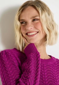 Pull en maille violet avec un motif en vagues texturé, col rond côtelé et poignets. Tissu doux et coupe décontractée. Aucun matériel notable.