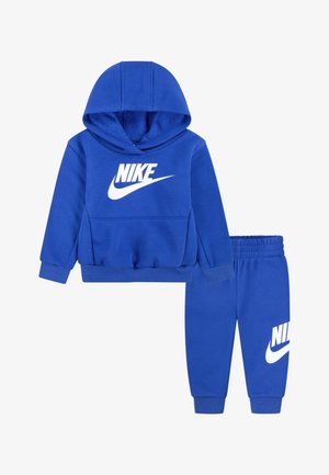 Σετ μπλε φόρμας Nike με φούτερ και matching παντελόνι. Το φούτερ διαθέτει μπροστινή τσέπη καγκουρό και λευκό λογότυπο. Μαλακή υφή, ελαστικά μανσέτα και ζώνη μέσης.