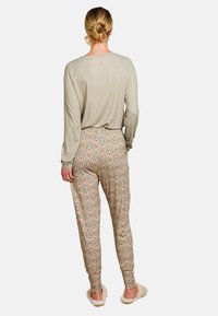Lichtgrijze lange mouwtop met geometrisch patroon, gecombineerd met gebloemde beige joggingbroek met patronen. Zachte textuur, casual pasvorm.