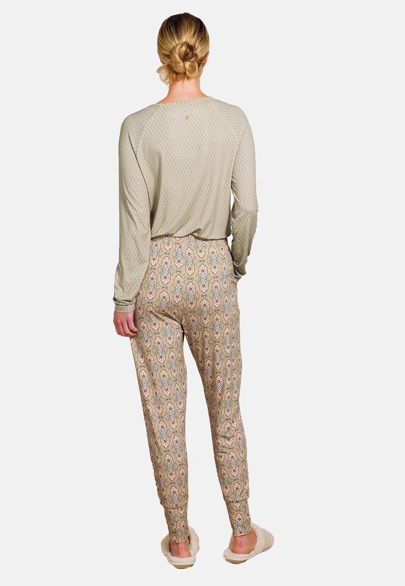 Lichtgrijze lange mouwtop met geometrisch patroon, gecombineerd met gebloemde beige joggingbroek met patronen. Zachte textuur, casual pasvorm.