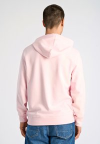 Ljusrosa hoodie i mjukt tyg, med en känguruficka, elastiska ärmslut och huva med dragsko. Baksidan har en enkel design.