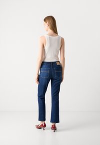 Sinised teksapüksid sirgete jalgadega, millel on kaks tagataskut ja nahkpatch. Kombineeritud valge tank-topp ja punased kõrged kontsad.