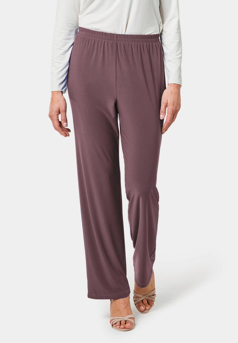 Bordeauxkleurige wijde broek met een elastische tailleband, gemaakt van zachte stof. Gecombineerd met een lichtgekleurde top en strappy beige sandaaltjes.