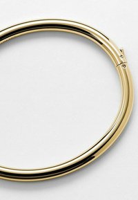 Bracciale in metallo dorato con forma liscia e arrotondata e un design senza soluzione di continuità. Presenta una superficie lucida e una chiusura a gancetto sottile.