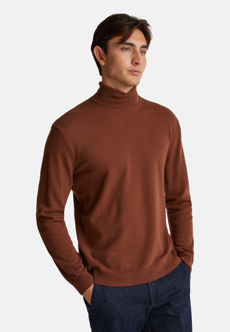 Brązowy sweter z golfem z miękkiego materiału, dopasowany krój, prążkowany kołnierz i mankiety, w zestawieniu z ciemnymi dżinsami dla casualowego wyglądu.