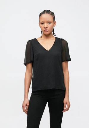 Juoda palaidinė su V formos iškirpte, trumpomis permatomomis rankovėmis ir laisvo silueto. Audinys yra švelnios tekstūros ir lengvas, tinkamas sluoksniavimui.