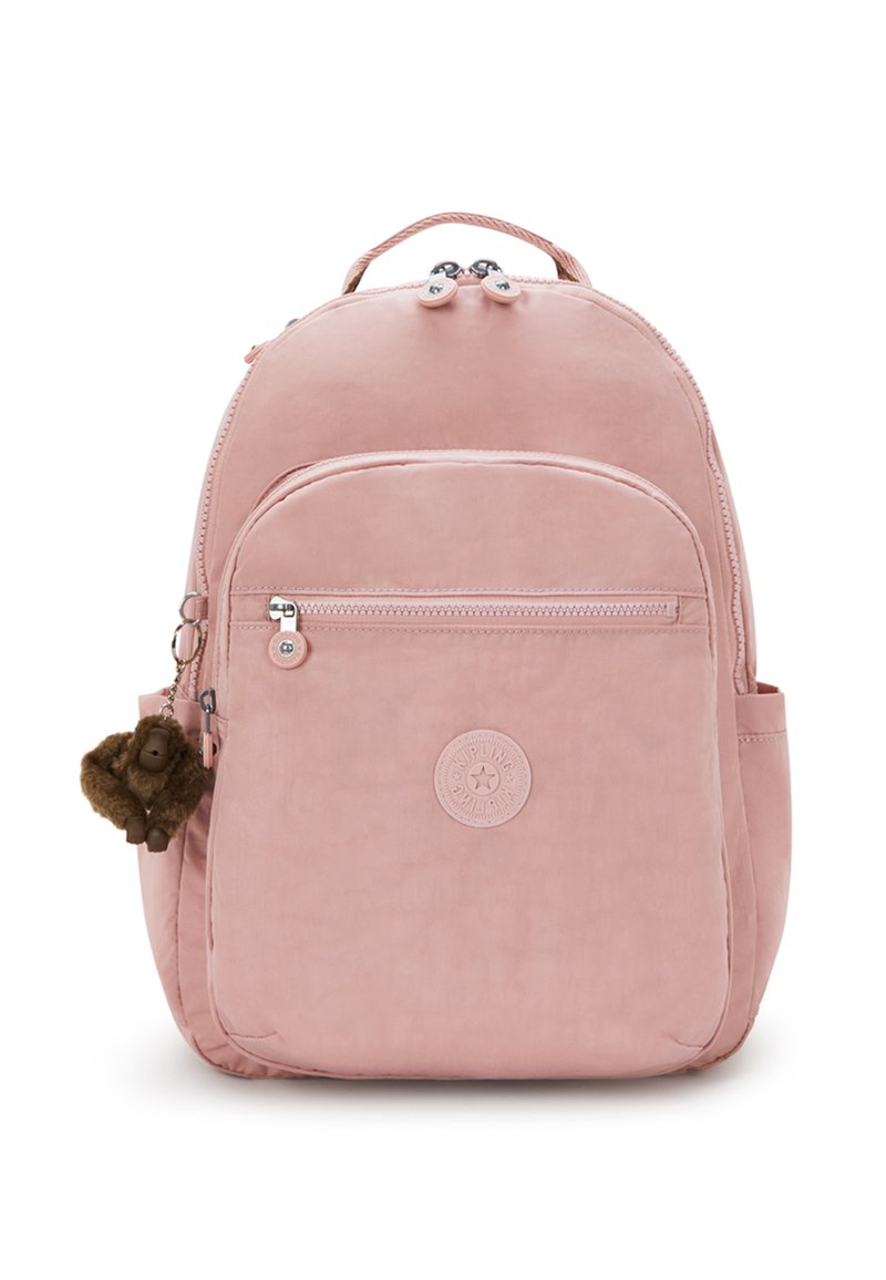 Sac à dos rose avec poche avant zippée, poches latérales, poignée supérieure et petit porte-clés singe en peluche marron attaché.