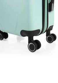 Maleta rígida de color verde menta con un acabado texturizado, equipada con cuatro ruedas negras y dobles cremalleras con detalles negros.