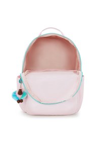 Světle růžový látkový batoh s tyrkysovým zipem, kulatého tvaru, a na přední kapse připevněný měkký, plyšový klíčový řetízek ve tvaru opice.