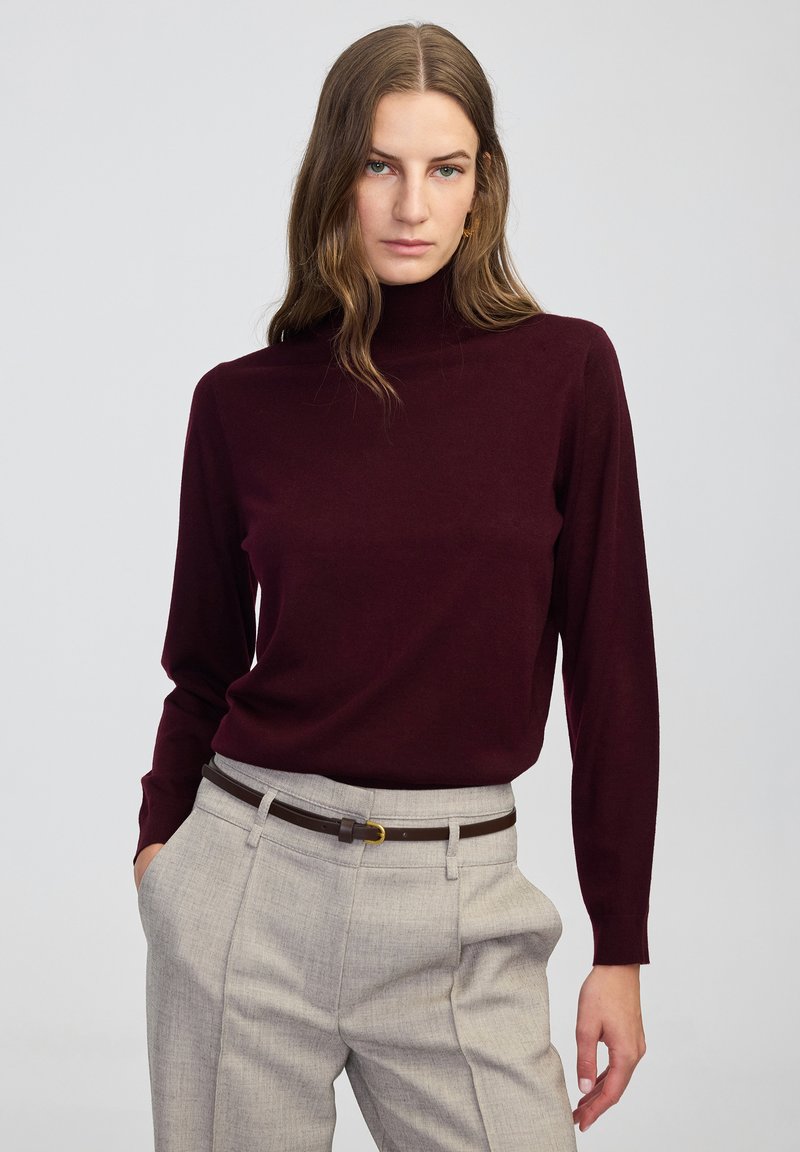 Bordowy sweter z golfem wykonany z miękkiego materiału, z długimi rękawami, połączony z jasnoszarymi, dopasowanymi spodniami i brązowym paskiem. Prosty i klasyczny design.