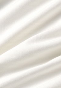Witte katoen stof met een gladde textuur, die subtiele plooien en vouwen toont, wat de lichtgewicht en zachte kenmerken benadrukt.