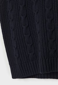 Mörk marinblå stickad tyg med vertikala kabel- och ribbmönster, som visar textur och stygn detaljer.