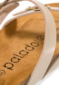 Ljusbeige lädersandal med en mjuk mockainsålin. Har tunna remmar och en spänne i mässing. Text på insålin märk "palada."