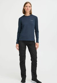 Langärmliges navy Hemd kombiniert mit schwarzen Cargo-Hosen, die mehrere Taschen, einen lässigen Schnitt und einen strukturierten Stoff besitzen.