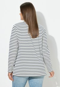 Gestreiftes Langarm-Top in Weiß und Marineblau, mit rundem Ausschnitt und lockerem Schnitt, versehen mit einem etwas längeren Rückensaum.