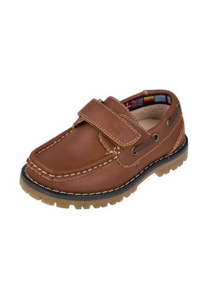 Zapato de cuero marrón con punta redonda, correa de Velcro, costura texturizada y suela de goma flexible. El interior presenta un patrón de banderas coloridas.