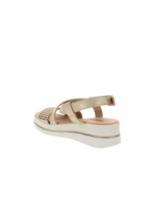 Sandale beige avec un design supérieur perforé, deux straps ajustables et une semelle en wedge de couleur claire avec des détails texturés.