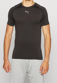 Svart kortärmad träningsskjorta med en åtsittande design. Har strukturdetaljer på axlarna och en reflekterande logotyp på bröstet.
