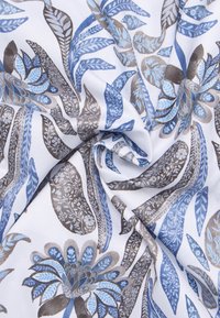 Geprinte stof met blauwe en bruine bloemen- en loofontwerpen op een witte achtergrond, met ingewikkelde details en een zachte textuur.
