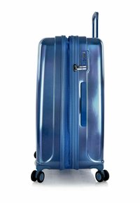 Blue hard-shell suitcase with a textured finish, zipper closure, built-in lock, side handle, and four black wheels for mobility.