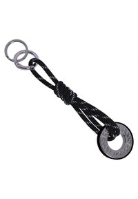Cordón trenzado en blanco y negro con un anillo metálico, presentando un acento circular grabado. Dos anillas metálicas más pequeñas están unidas.