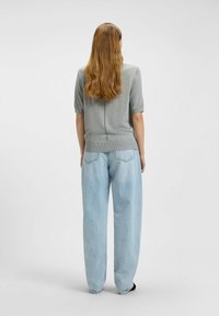 Light gray knit top with short sleeves and a back seam, paired with loose-fitting light blue jeans. Soft texture and casual design.