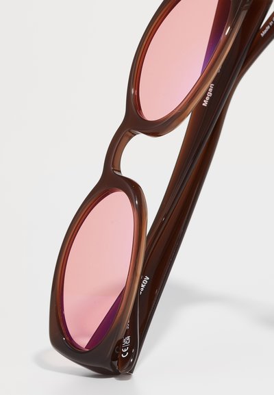 Ochelari de soare din plastic maro cu lentile ovale roz și părți elegante. Prezintă o textură netedă și un logo discret pe brațe.