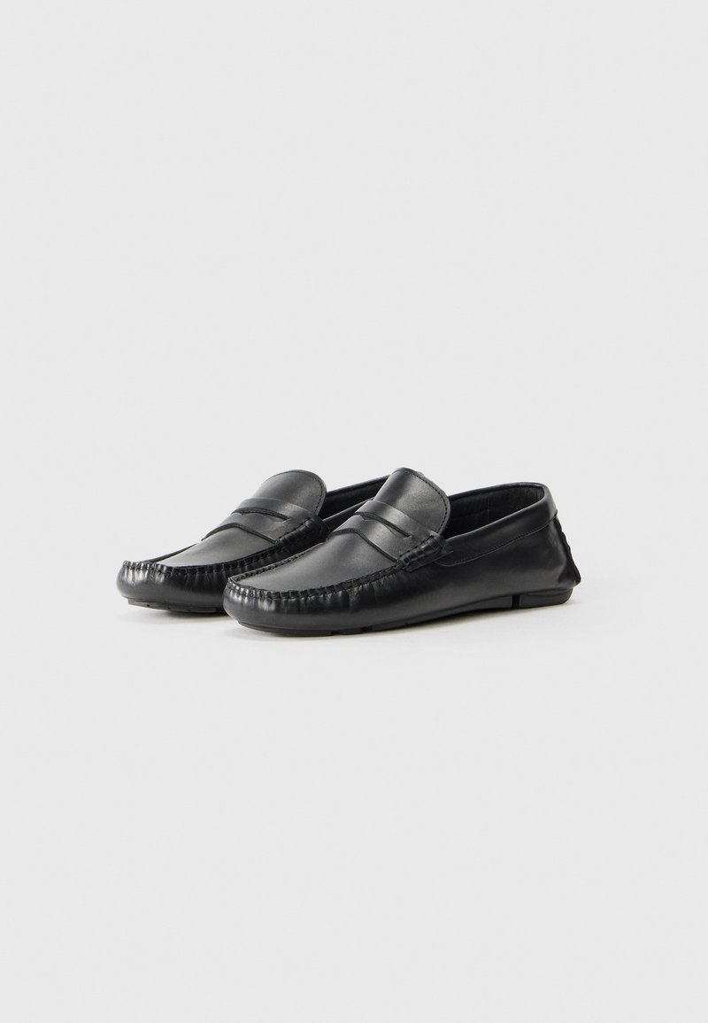 Mocassini in pelle nera con design mocassino, caratterizzati da dettagli cuciti, una texture liscia e una suola in gomma a profilo basso.