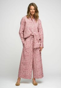 Completo con motivo floreale composto da una camicia rosa ampia e pantaloni a gamba larga. Realizzato in tessuto leggero con una morbida texture.