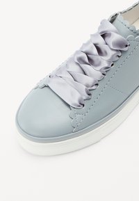 Lys blå sneakers med en glat læderfinish, som har satinbåndsnørebånd, scalloperede detaljer og en hvid gummisål.