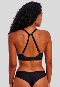 Schwarzer BH mit glatter Textur, ausgestattet mit einem Racerback-Design und verstellbaren Trägern. Inklusive Hakenverschluss auf der Rückseite.