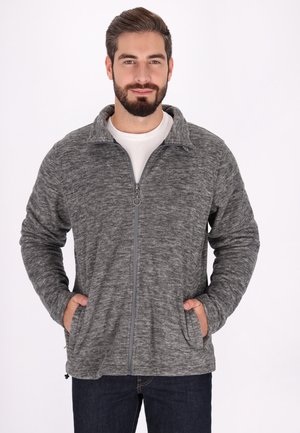 Graue Fleecejacke mit Reißverschluss, strukturiertem Finish, Stehkragen und Seitentaschen, getragen über einem weißen Hemd. Weicher, warmer Stoff.