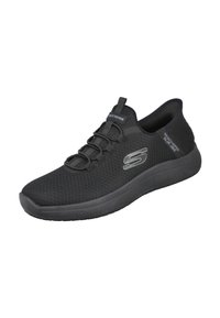Zapatilla deportiva negra con parte superior de malla transpirable, cordones elásticos y suela de goma. Presenta un logo en el lateral y una superficie texturizada.