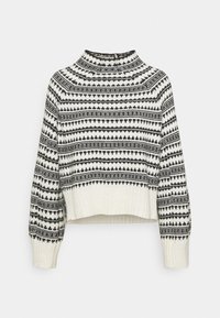 Pull court blanc avec motifs géométriques et points noirs, poignets et ourlet côtelés, et un col montant court.